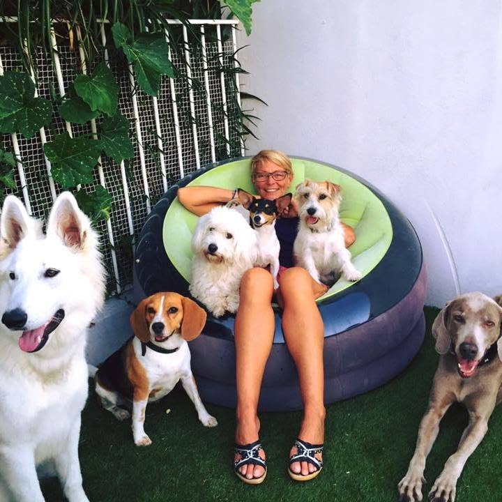 Corinne entourée de plusieurs chiens dans le jardin de la pension